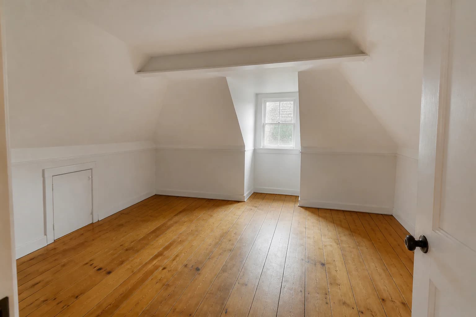 Empty attic bonus room with sloped ceilings, dormer window, low access door, and pine floor